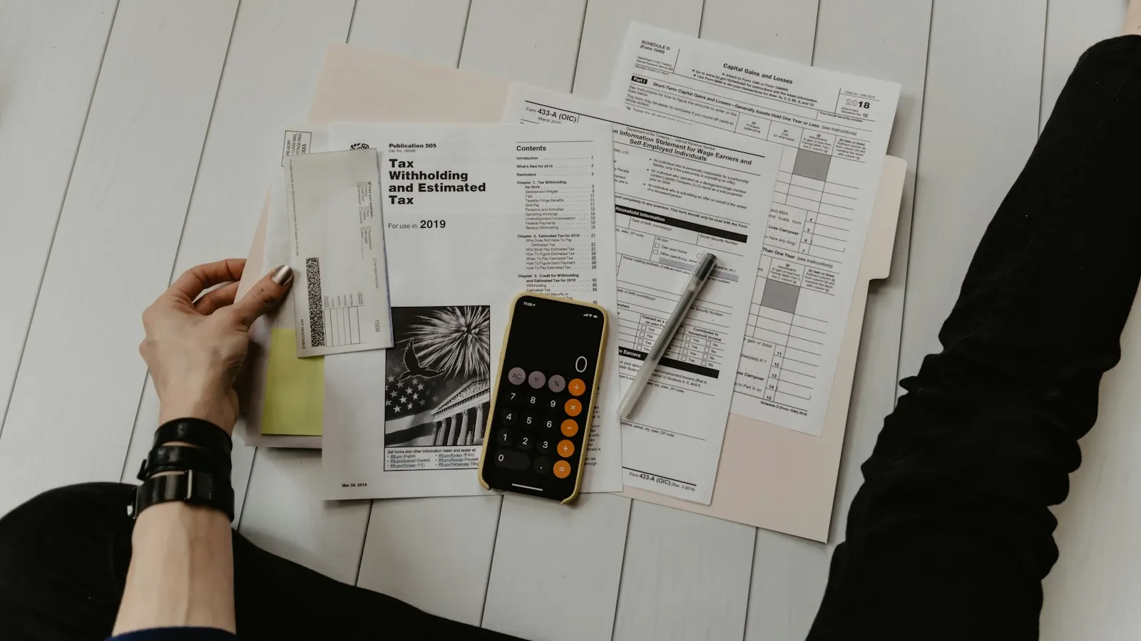 Tax forms, a phone calculator and a pen on a desk