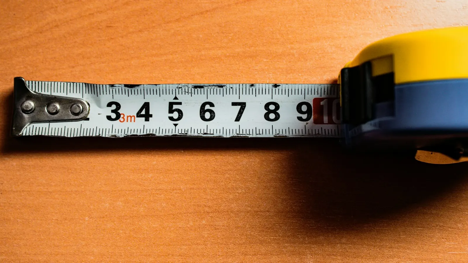 A tape measure extended across a wooden table