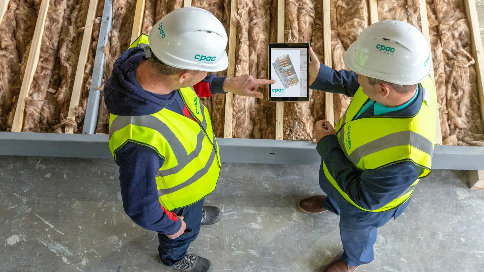 Two construction workers reviewing plans on a tablet