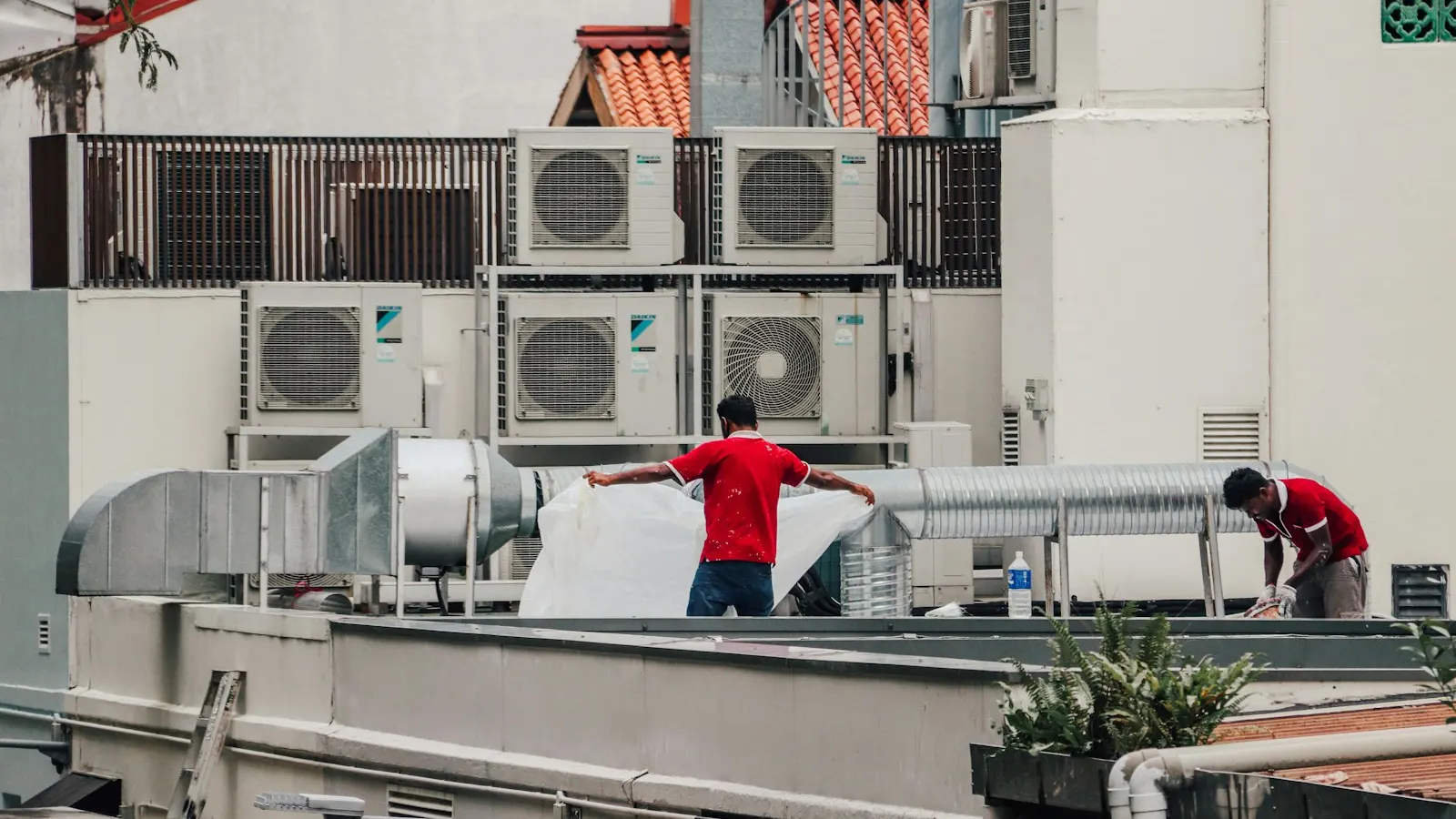 Technicians working among air conditioning units on a rooftop