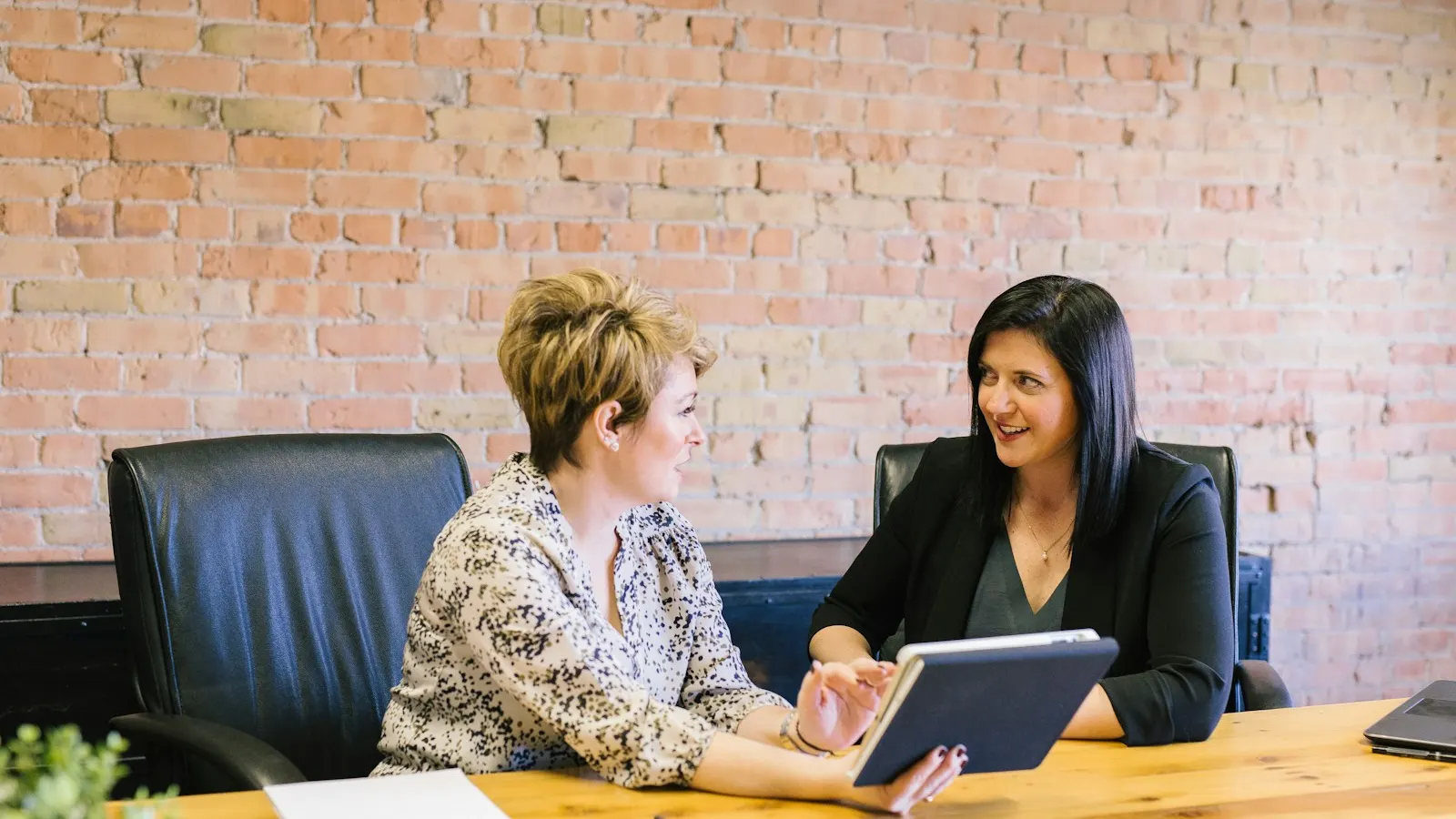 A financial advisor meeting a client at a desk with a tablet
