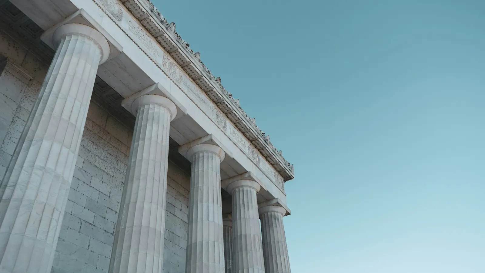 Neoclassical columns of a government building against a blue sky