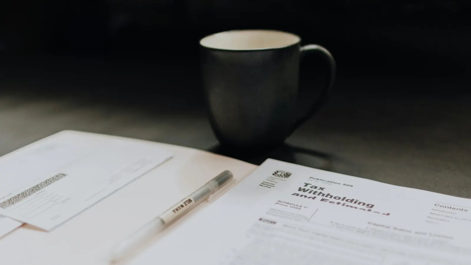 Tax withholding papers and a coffee mug on a desk