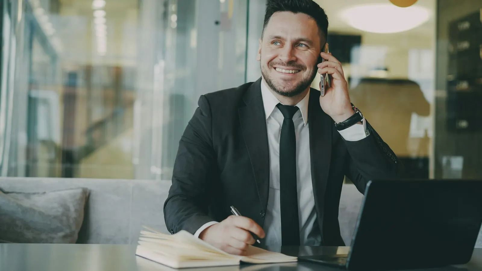 A lawyer in a suit on the phone at a desk with a laptop