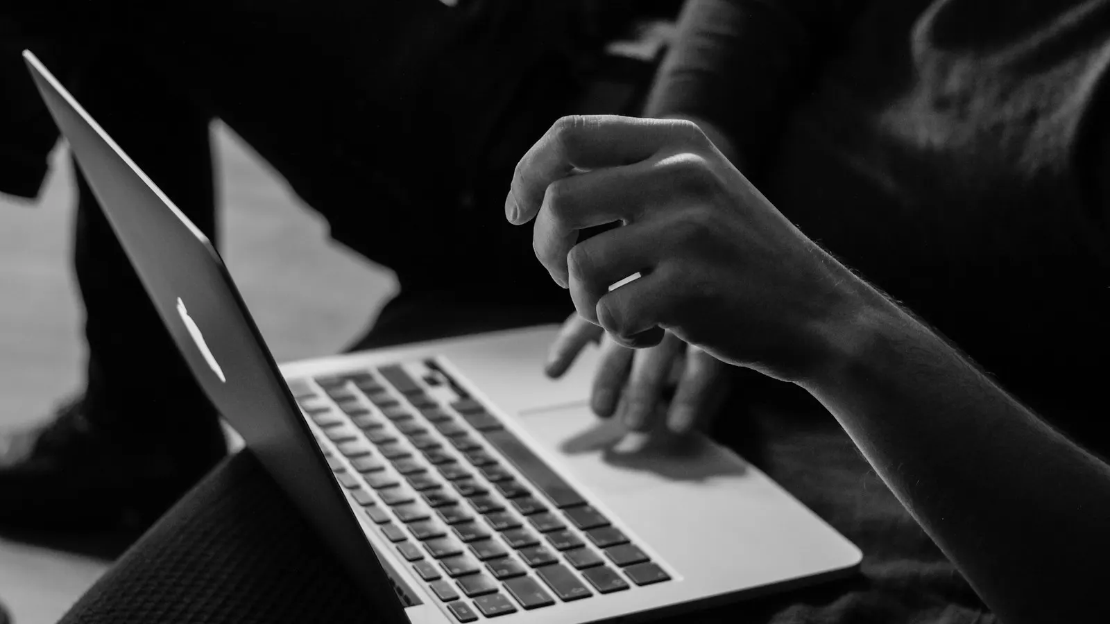 A person typing on a laptop in black and white