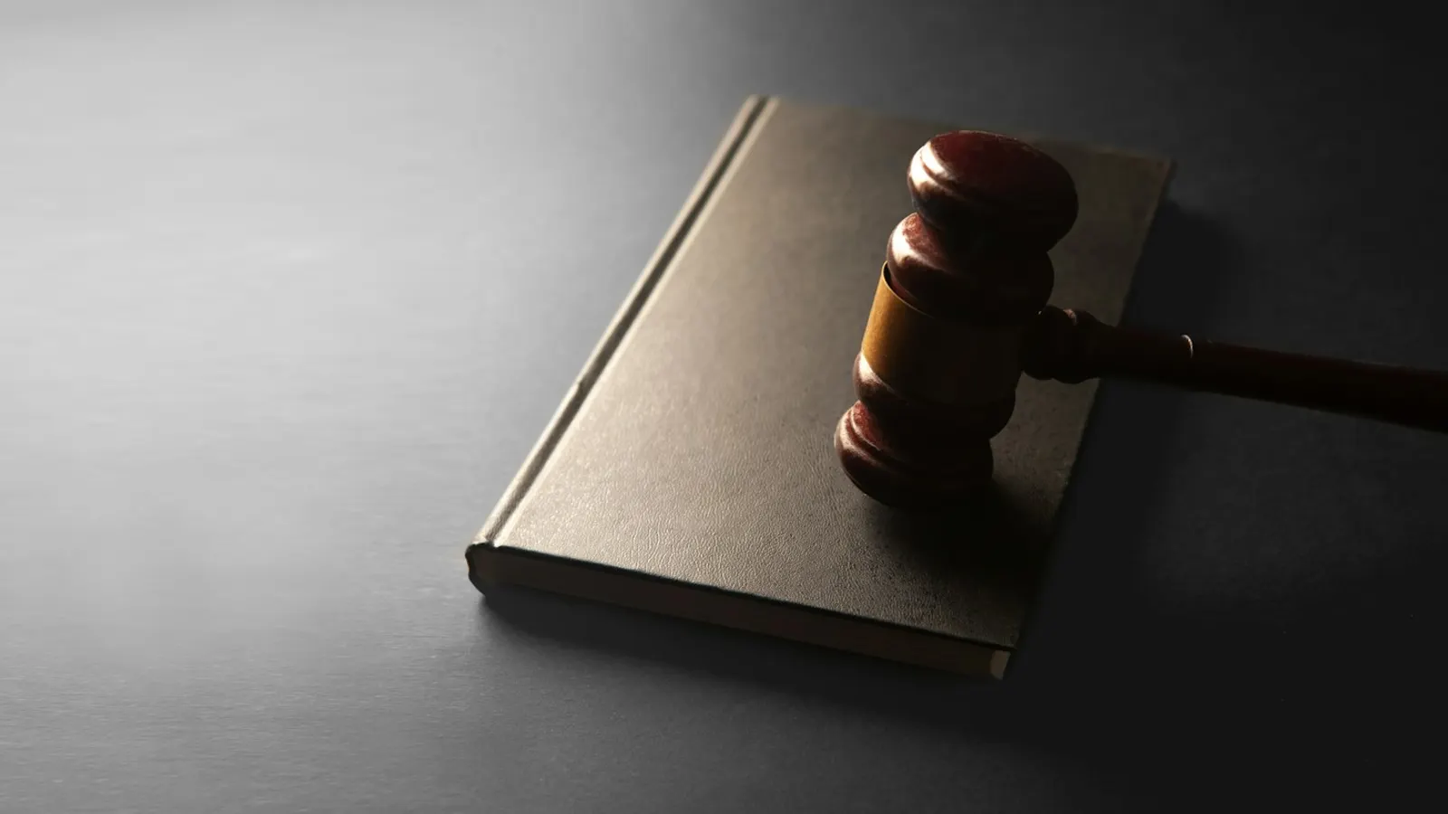 A wooden gavel resting on a closed book