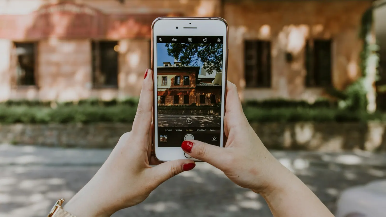 A person photographing a house with a smartphone