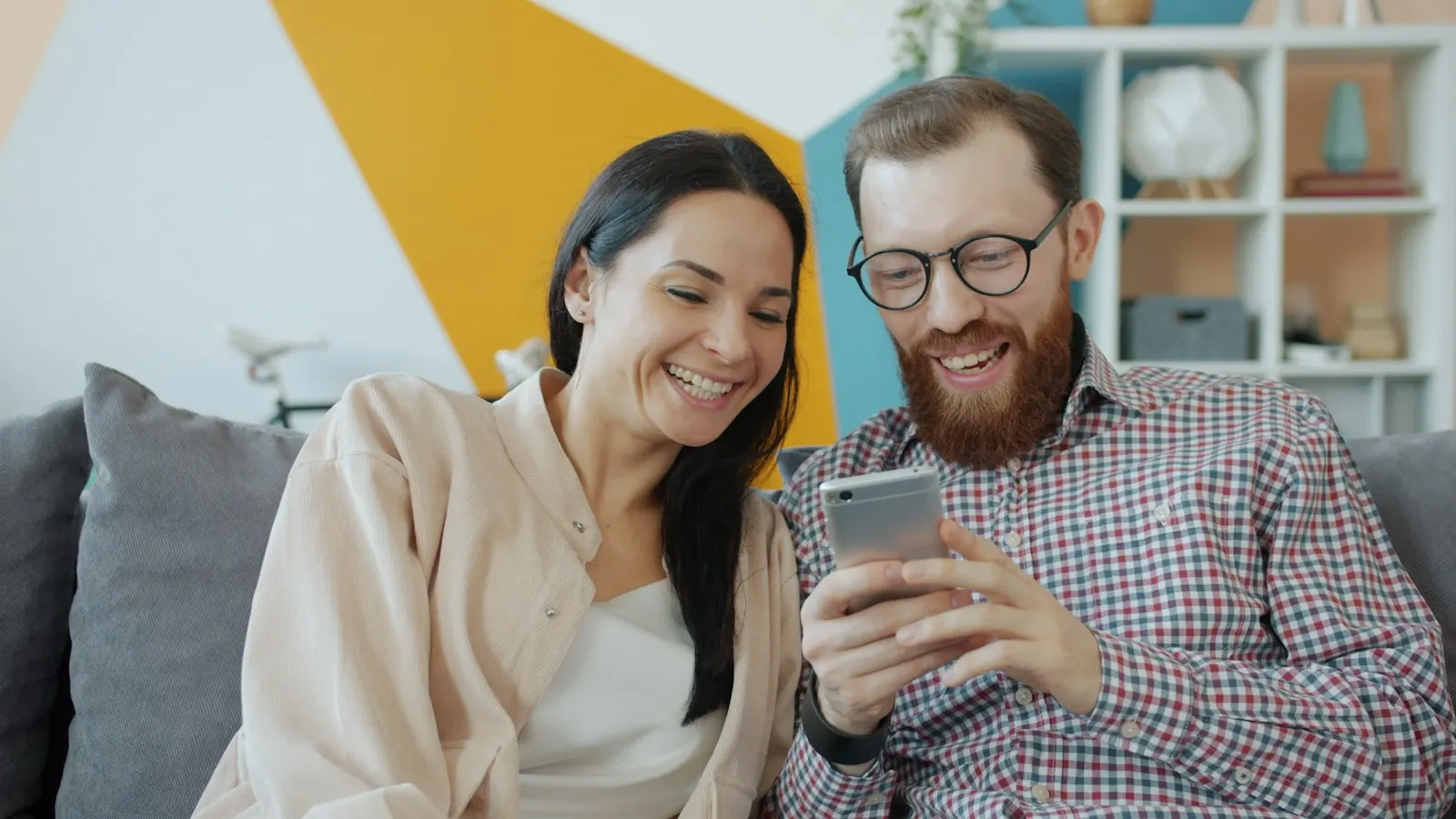 A couple smiling while browsing on a smartphone together