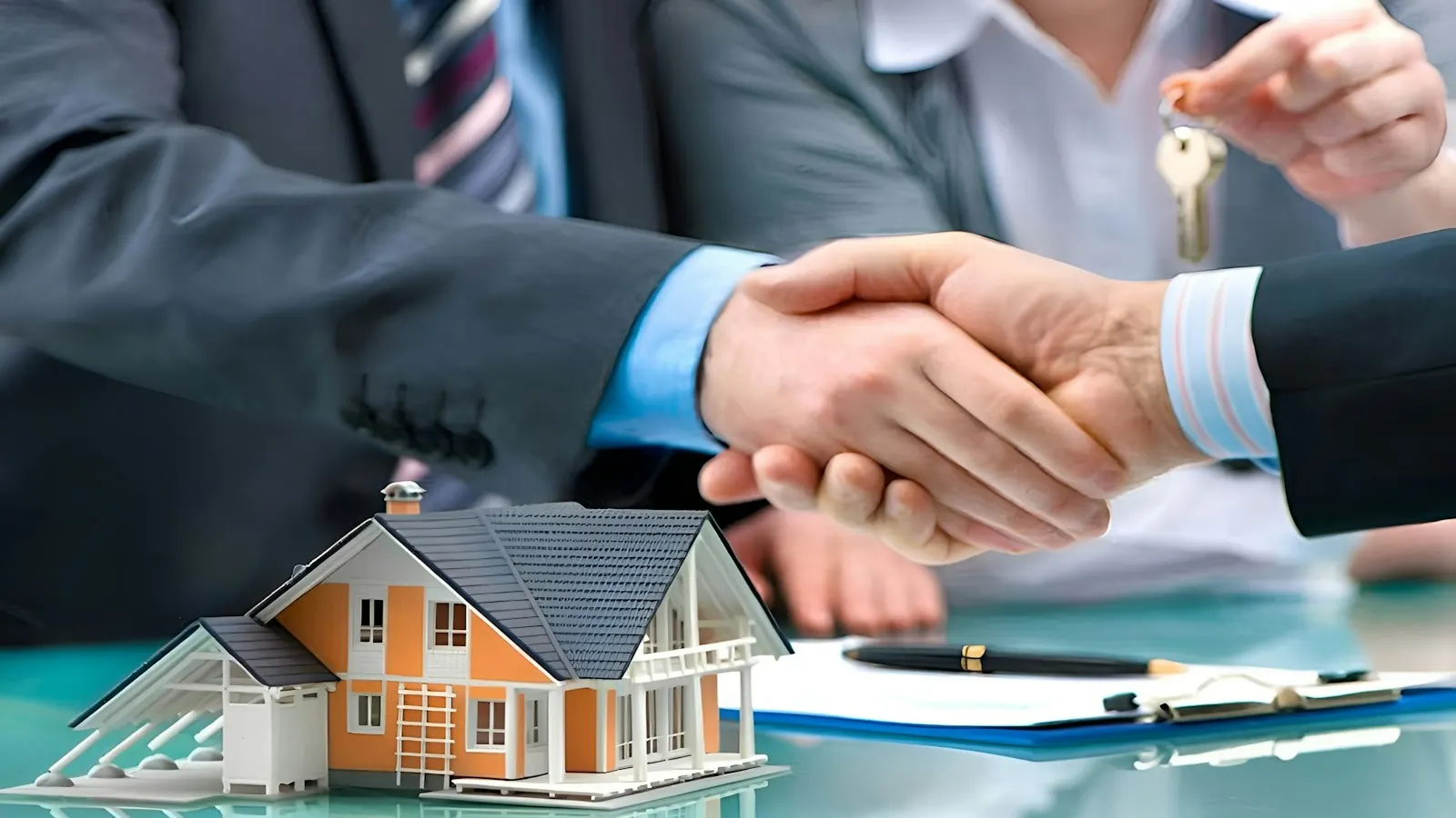 A handshake over a model house and a set of keys