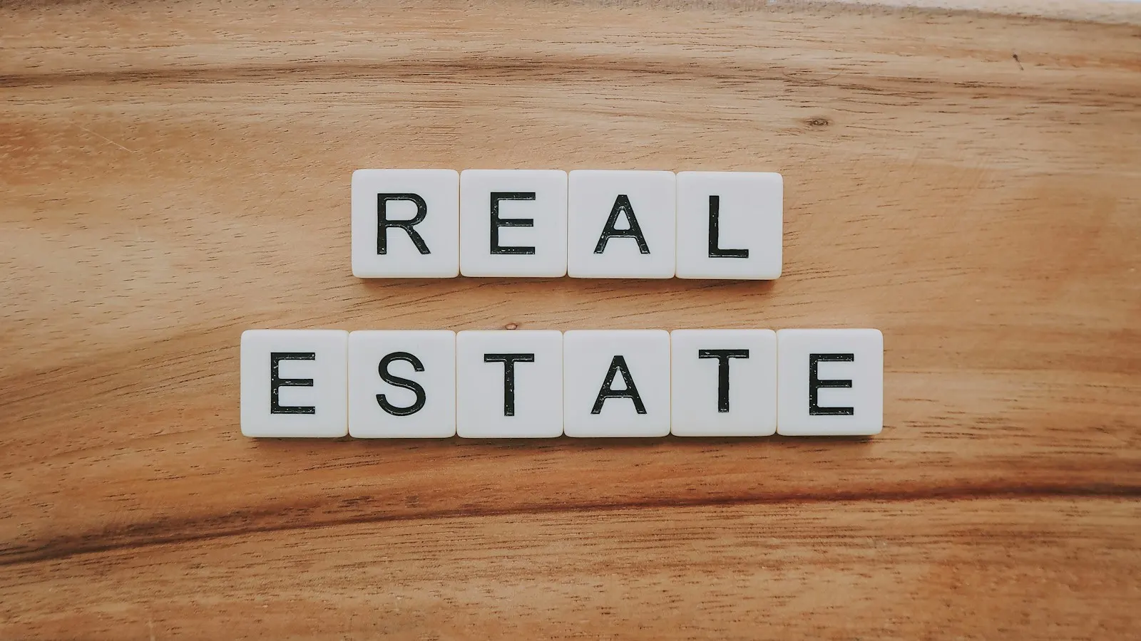 Letter tiles spelling REAL ESTATE on a wooden table