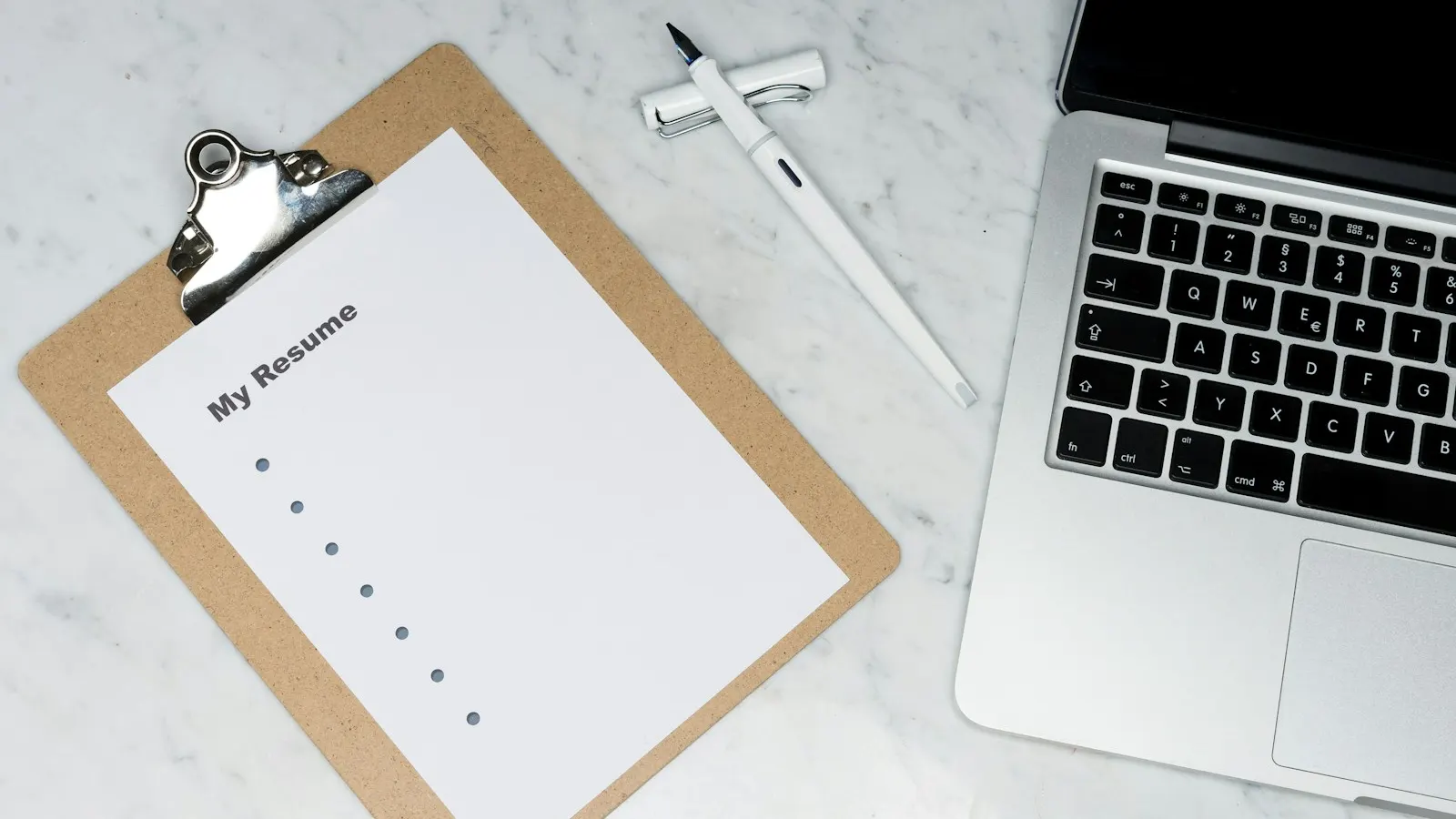 A resume on a clipboard beside a laptop