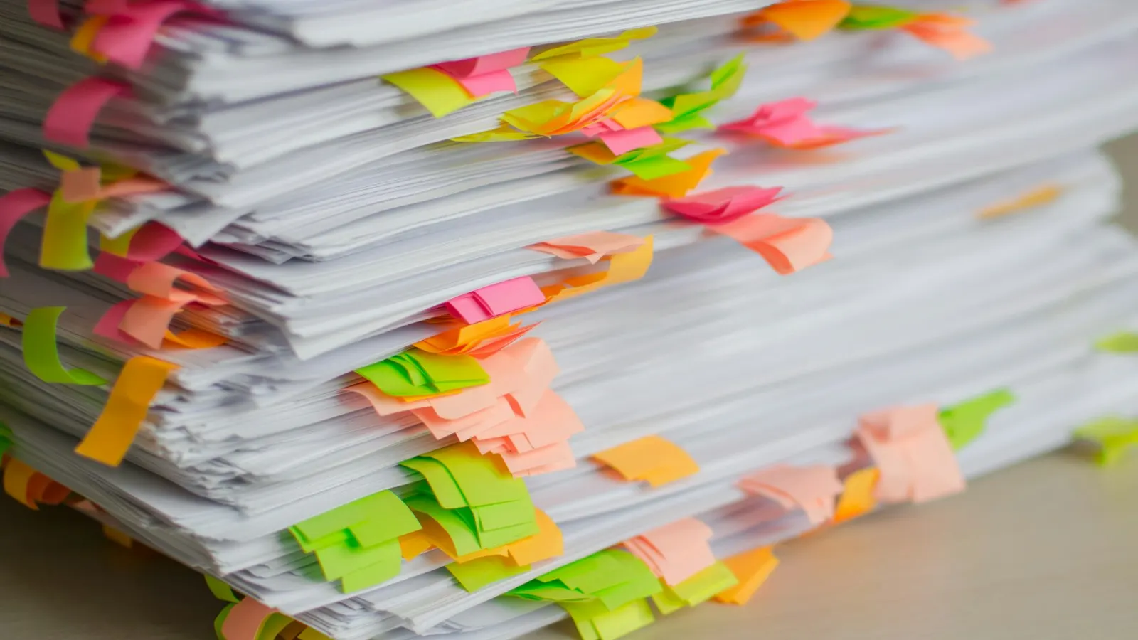 A tall stack of documents marked with colorful sticky tabs
