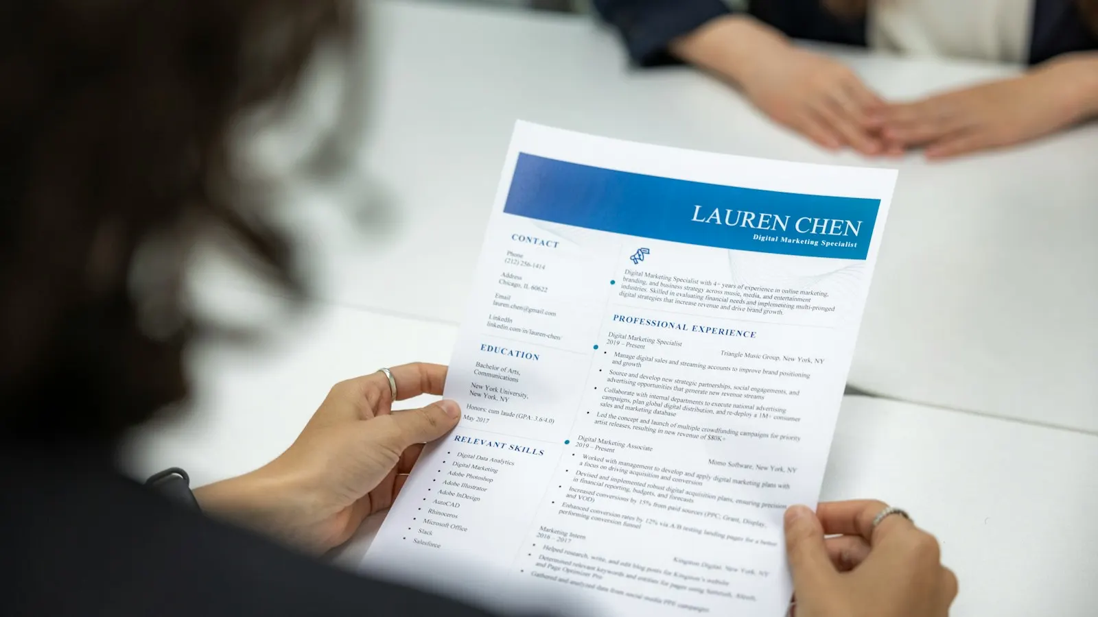 A woman reading a printed resume at a table