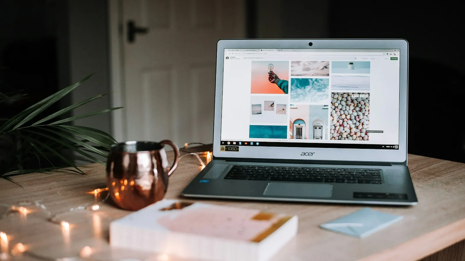 A laptop on a table beside a copper mug