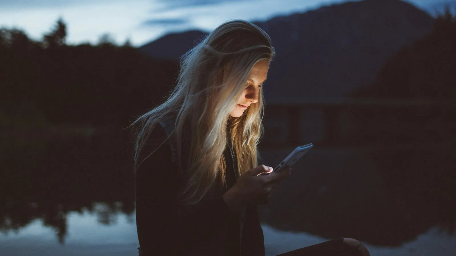 A young woman looking at her phone at dusk