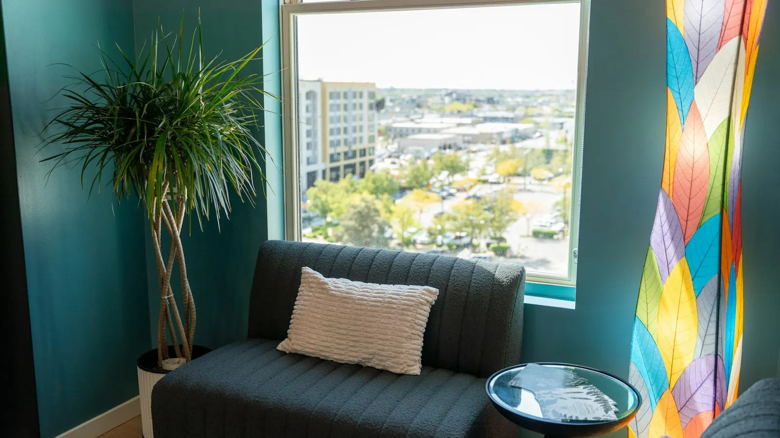 A calm counseling room with a sofa, a plant and a window