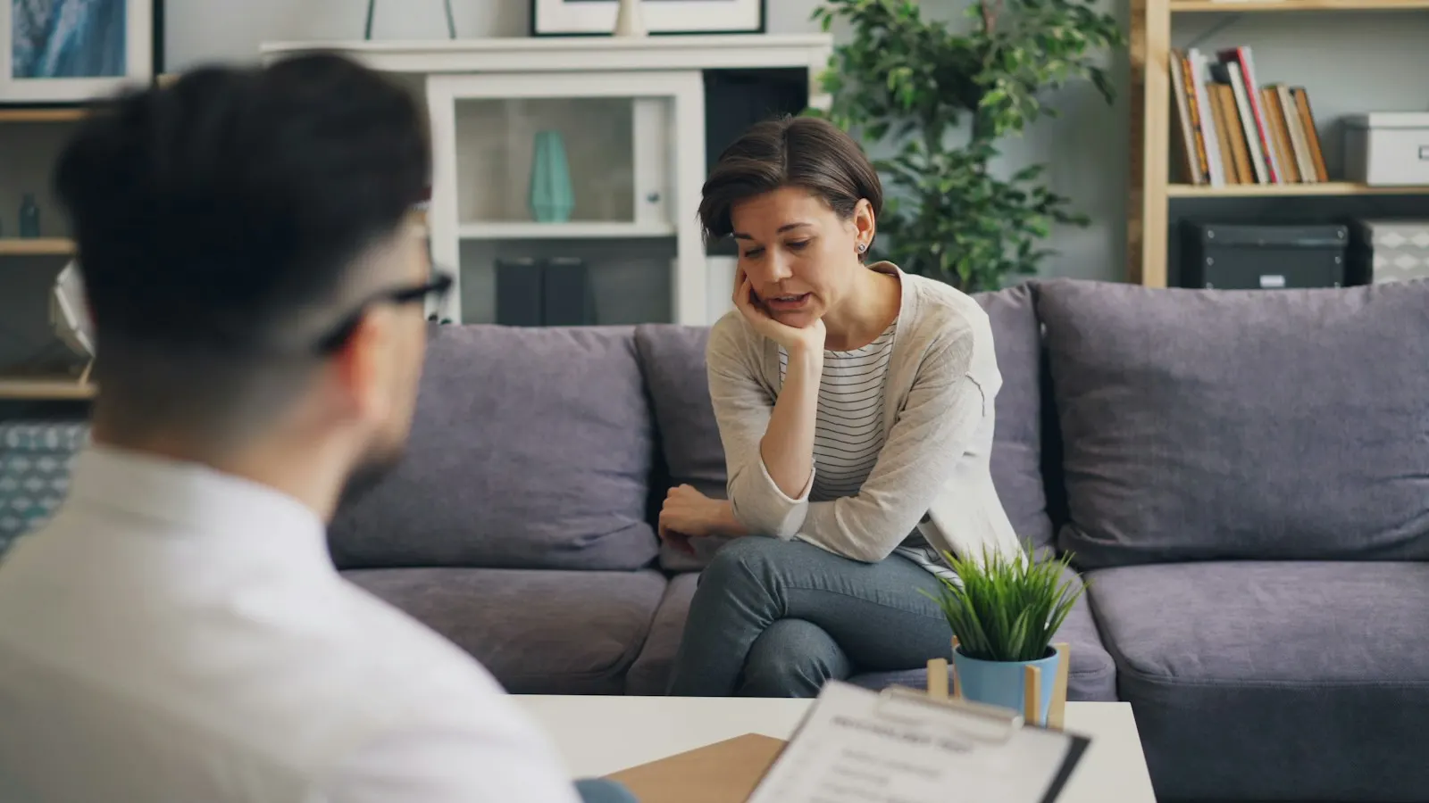 A therapist listening to a client seated on a sofa